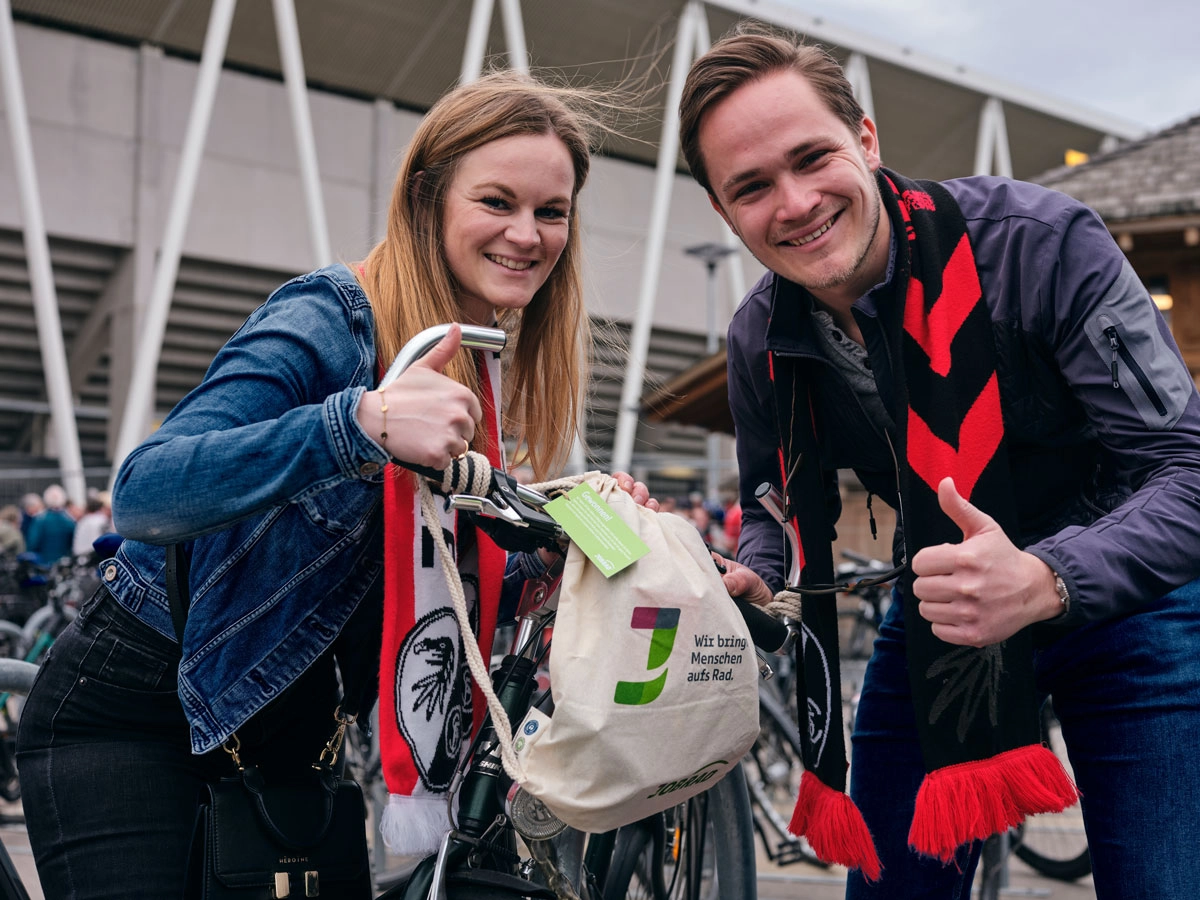 Ein Mann und eine Frau halten eine Goodie Bag am JobRad Aktionsspieltag Klimaschutz und machen beide die Daumen hoch Geste Ein Mann und eine Frau halten eine Goodie Bag am JobRad Aktionsspieltag Klimaschutz und machen beide die Daumen hoch Geste